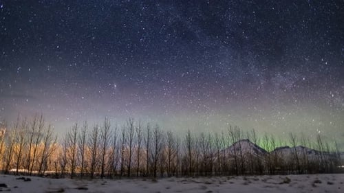 Night Sky Stars and Aurora Borealis Over Snowy Landscape