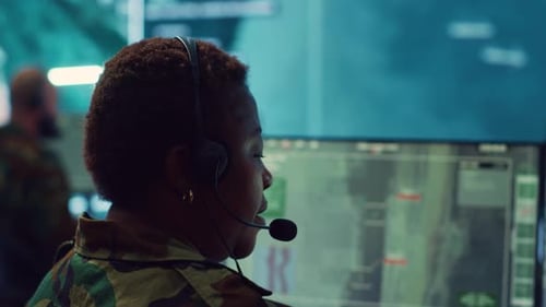 Woman Wearing Headset Looks at Computer Monitors