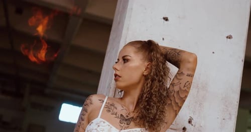 Tattooed woman with fire explosion in the background, posing for the camera close up