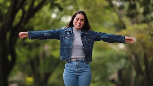 Joyful Brunette Woman Celebrates with Raised Arms in Park