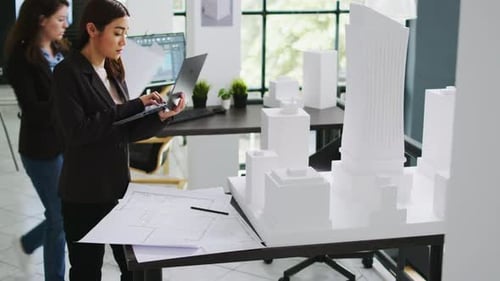 Asian Contractor Takes Notes About 3d Printed Model on Laptop