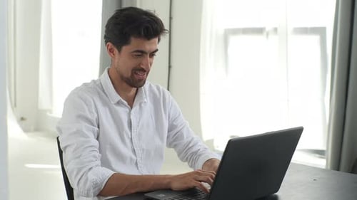 Man Typing on Laptop at Table