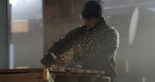 Man Grinding Metal with Angle Grinder Indoors