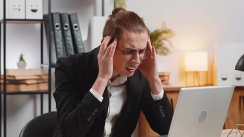 Sick Young Businessman Working on Laptop Feeling Headache Rubs Temples Sitting at Home Office Desk