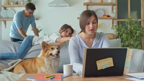 Woman Working on Laptop at Home with Family
