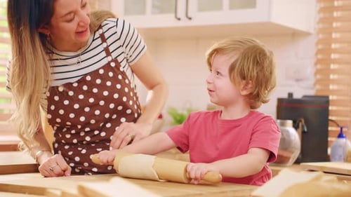 Caucasian attractive mother baking bakery with son in kitchen at home.