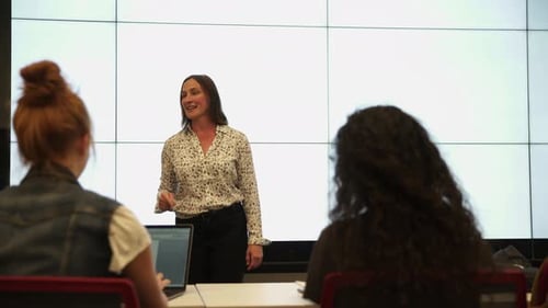 Enthusiastic teacher explaining lesson to students in university classroom
