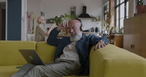 Senior Man Listening to Music on Laptop at Home