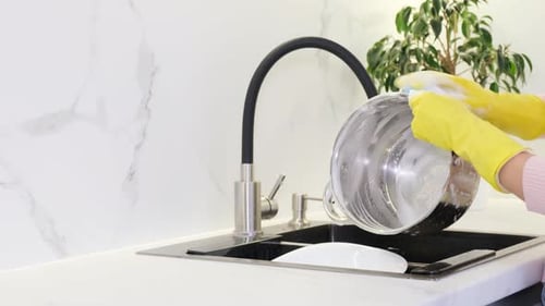 Person Washing Pot in Kitchen Sink
