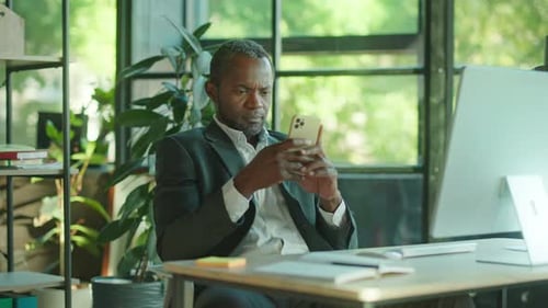 Close Up Handsome African American Man is Using Smartphone Texting to Communicate Online Sitting at