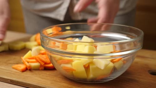 04sm. Place raw chopped potatoes and carrots in a bowl. Preparation of a vegetable dish. Slow motion