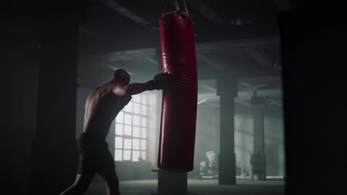 African american boxer trains with punching bag in dark gym for strength and power