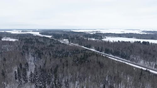 Aerial View of Snowy Forest and Roadway in Winter