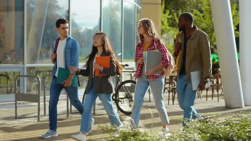 Four Mixedrace Young Students Walking on Sunny Street Communicating Sharing Stories Laughing