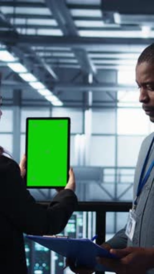 Vertical Video Technicians in Data Center Using Green Screen Tablet Reviewing Hardware