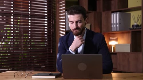 Hübscher Geschäftsmann arbeitet am Laptop am Holzschreibtisch im Büro