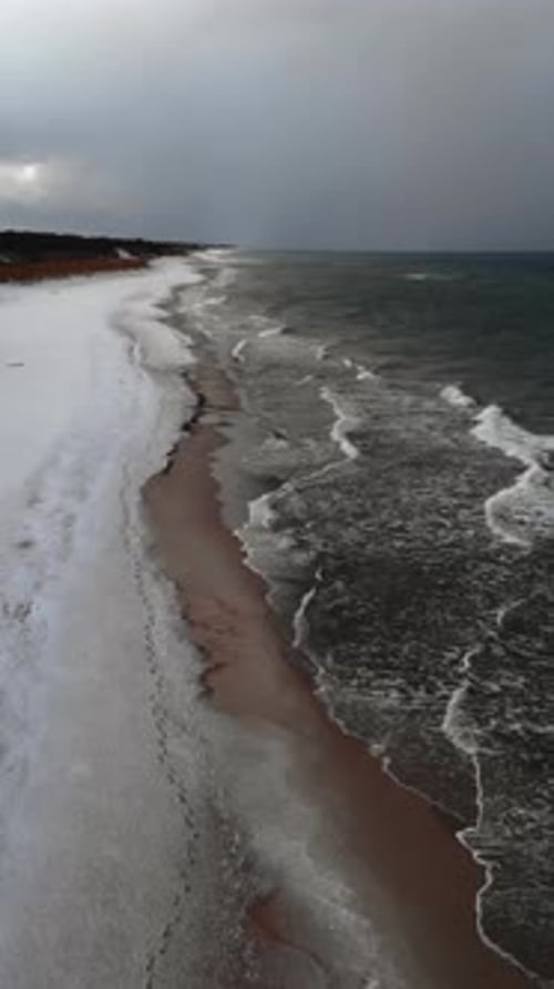 Aerial View of a Snowy Beach with Stormy Ocean Waves Media
