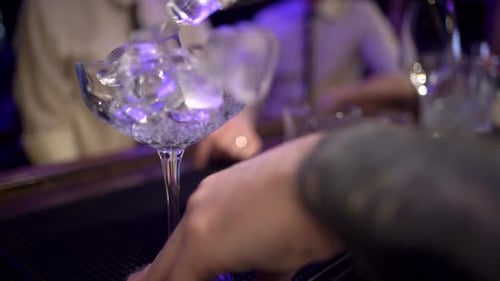 Ice Cubes Added to Cocktail Glass at Bar