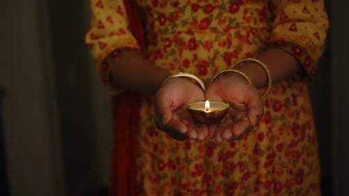 Woman Holding Lit Diya Lamp in Hands