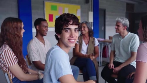 Portrait of Young Man Sitting in Circle Next to His Schoolmates at Class Looking at Camera Smiling