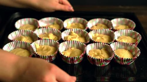 Chef takes baking tray with cupcakes in preparation for delicious dessert recipe
