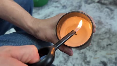 Man Lights a Scented Candle with a Lighter