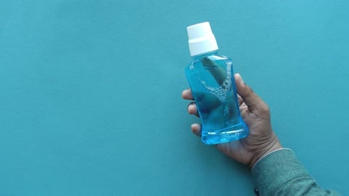 Hand Hold a Mouthwash Liquid Container
