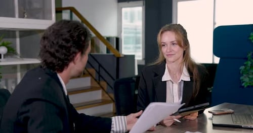 Businesswoman holding tablet discussing document with businessman during office meeting