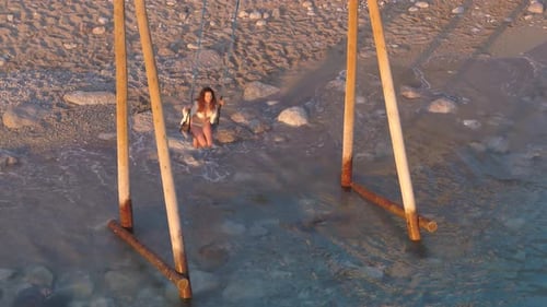 women at the beach on the swing sunset time