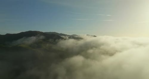 Flying through the clouds above mountain tops.
