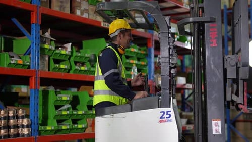 Warehouse worker controlling forklift in warehouse