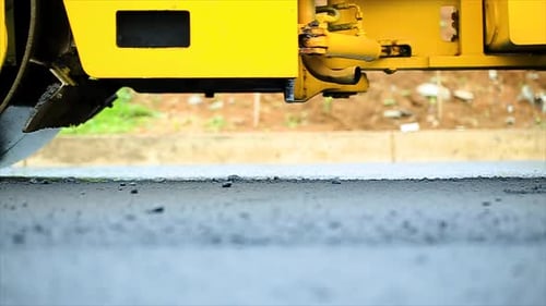 Les ouvriers compactent l'asphalte à l'aide d'un rouleau tandem roulant, qui est un type de compacteur lourd