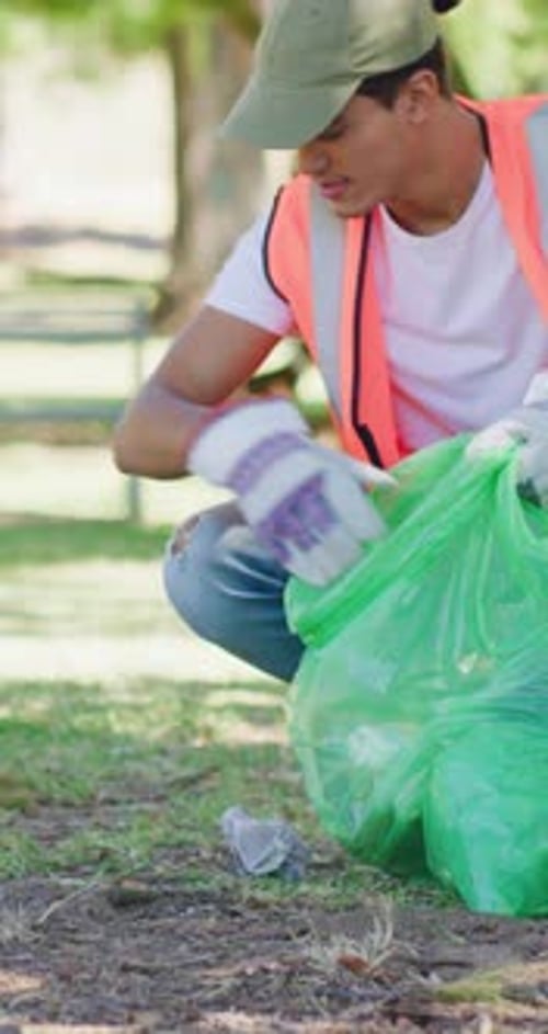 Voluntario, hombre y limpiando basura en el parque con bolsa de basura, proyecto sin fines de lucro