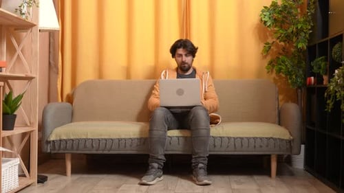 Man Sitting on Couch Using Laptop