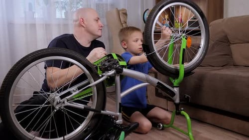 Man and Boy Repairing Bicycle Together Indoors