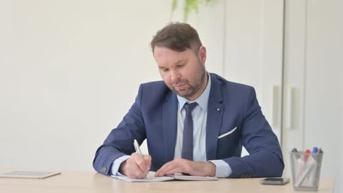 Man in Suit Writing at Office Table