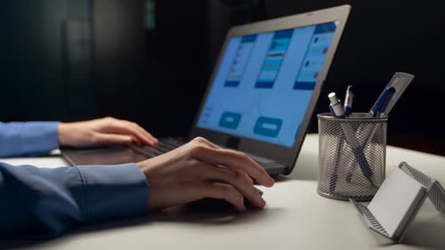 Web designer works late into the night on user interface laptop at office