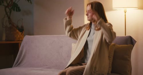 Tired Woman Sits Down on Sofa Leaning on Back in Living Room