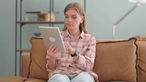 Woman Relaxing at Home Using Tablet Device