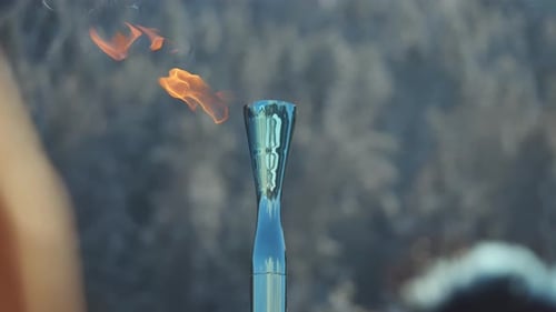 Nahaufnahme einer olympischen Fackel mit brennender Flamme während einer Staffel in den Dolomiten. Kultige Sportarten