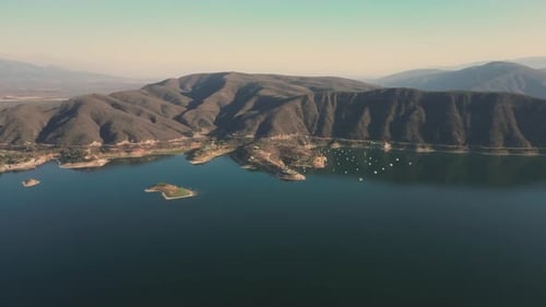 Aerial drone flying over a lake, water dam, with mountains at sunrise. Beautifull dreamy landscape.