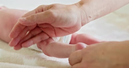 Adult Hand Adjusting an Infant's Diaper