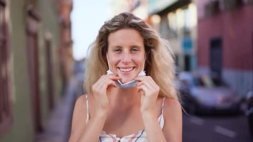 Smiling woman puts on a blue face mask