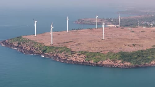 Aerial view of a coastal wind farm with wind turbines generating renewable energy on a cliff by the