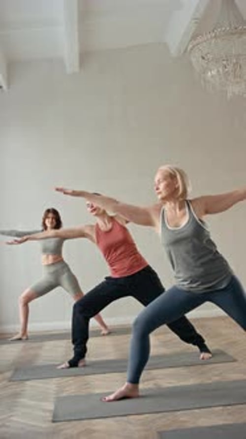 Trois femmes effectuant la pose de Trikonasana pendant un cours de yoga