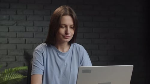 A Young Woman is Working on a Laptop Sitting in the Studio A Female Freelancer is Corresponding with