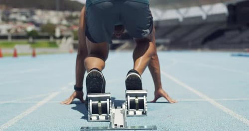 Athlete in starting position for a race on a sports track in a stadium