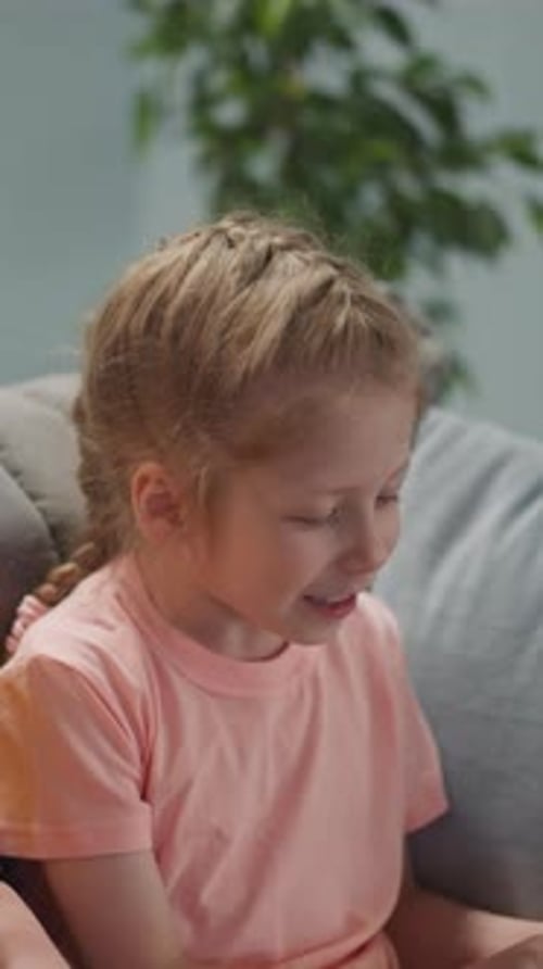 Smiling Blonde Girl Sitting on Couch with Adult