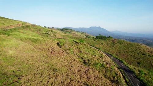Aerial drone view of a road winding through vast grassy mountains