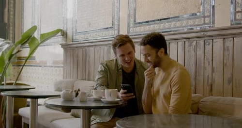 Male Gay Couple on Date Looking at Phone in Cafe